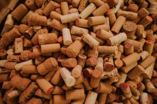 Weinglas und herausgezogener Naturkorken auf einem Holztisch
