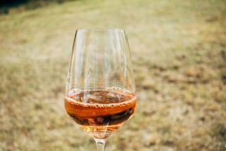 Glas mit bernsteinfarbenem Orange Wine neben einer Weinflasche